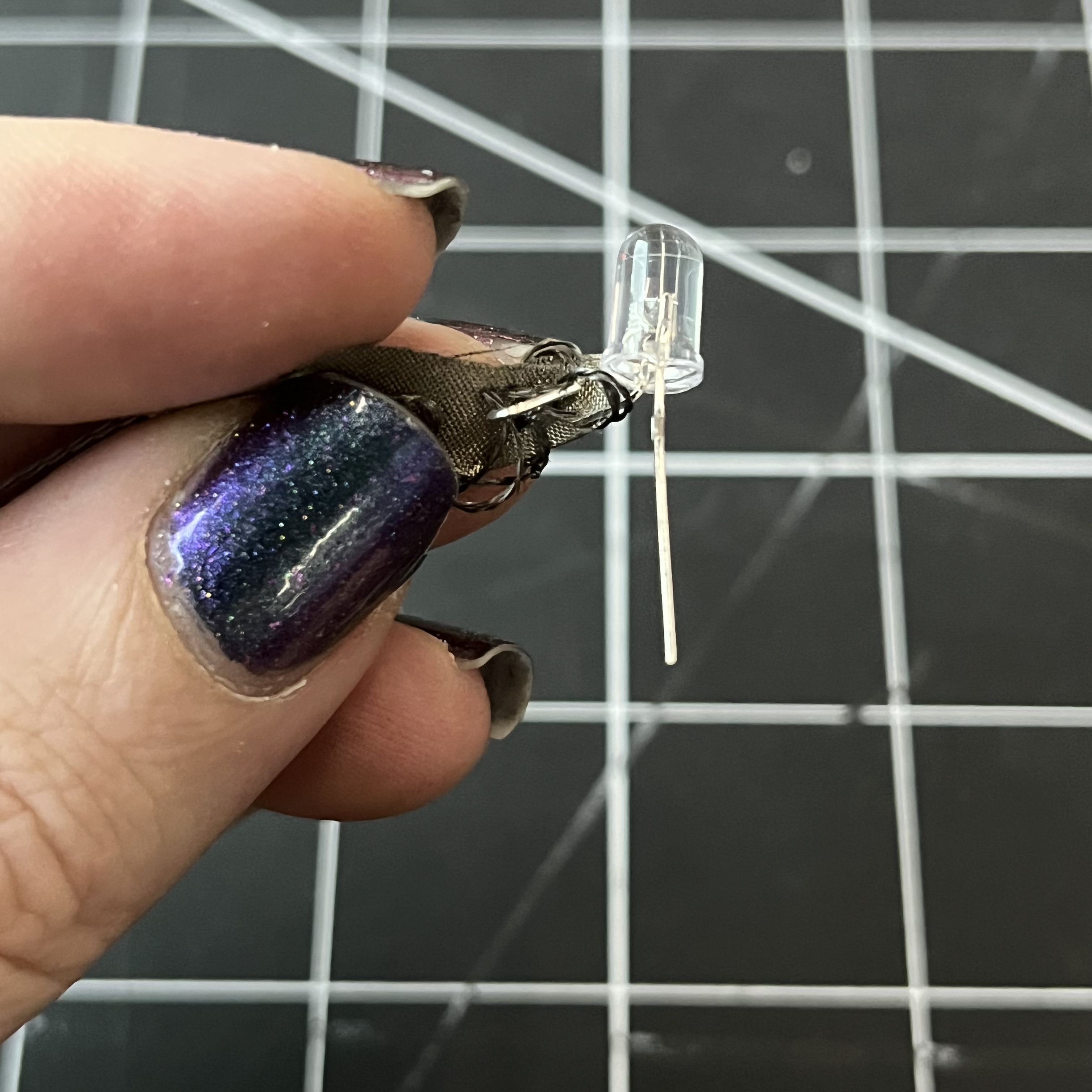 Next I made a ribbon circuit as a basic way to test other materials. Sewing this with conductive thread was rough, because the thread isn't smooth and very springy so I was constantly fighting with it to try and lay it smoother. I gave up on making it pretty and just aimed for functional because it wasn't worth spending the time on something that is just for testing and learning. I made it work by looping one of the metal wire ends of the LED and sewing conductive threat through the loop and the fabric over and over. I made approx 10-15 loops with the thread before tying it off and cutting it.