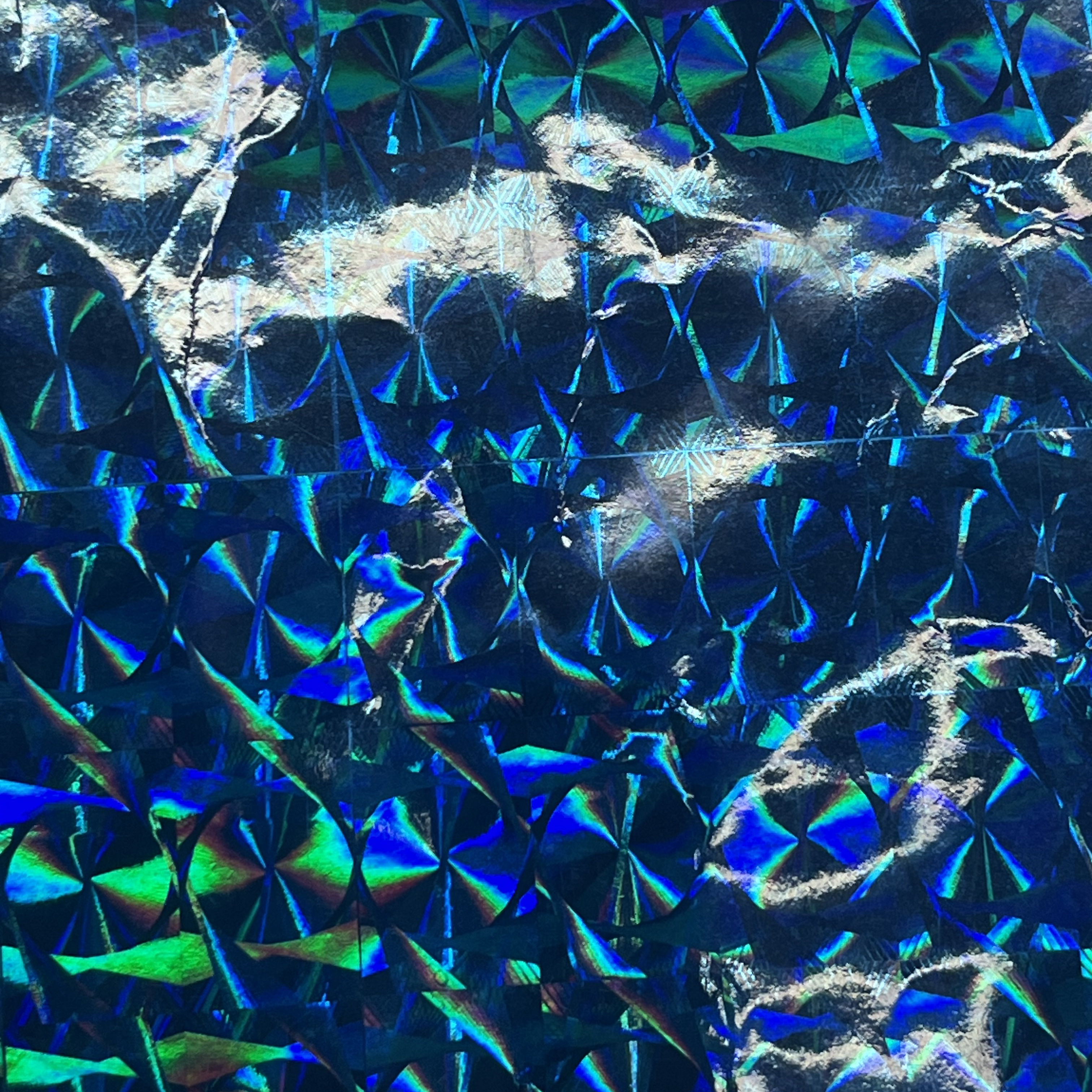 I love holographic things, and while I don't have a video of this, the image shows how reflective this material is. It's very fun to look as the different layers of holographic film create different shapes depending on the angle of the light. The actual material is very sleek with low surface tension, but it's been crinkled slightly created sharp contours in the light and a more visually interesting form along all the peaks the light hits.